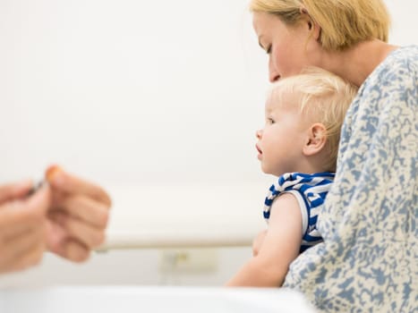 child beeing vaccinated by pediatrician in presence of his mother. Preventive vaccination against Diphtheria, whooping cough, tetanus, hepatitis, haemophilus influenzae, pneumococcus, poliomyelitis.