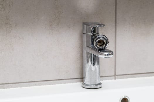 Broken tap in the bathroom sink. Splashing water from a silver faucet. Selective focus