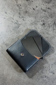 Black leather cardholder on a gray background. Handmade leather products.