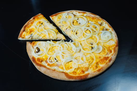 Sliced pizza with onion and meat, tomato sauce, mozzarella, onion and edge of dough, filled with cream cheese on a black background