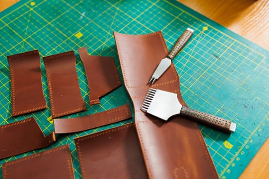 The process of production of leather goods. Materials and tools for leather production. Beautiful brown leather products and tools for needlework.