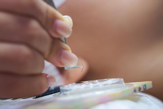Master hand takes accessories with tweezers tools for eyelash extension