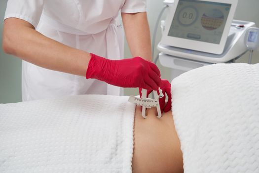 Woman measuring patient body fat with caliper