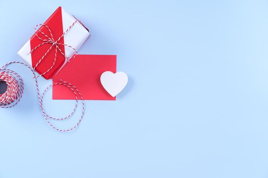 Valentine's Day, Mother's day art design concept - Red, white wrapped gift box isolated on pastel light blue color background, flat lay, top view.