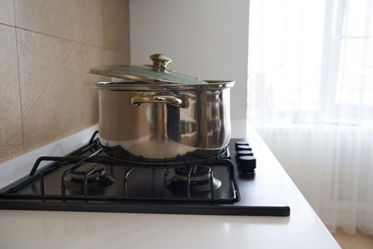 pan is on the stove in kitchen interior, Stainless steel pot. Cooking utensils concept