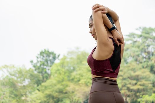 Back of Sport woman do arm and back stretching in park or garden and she look to left side with day light.