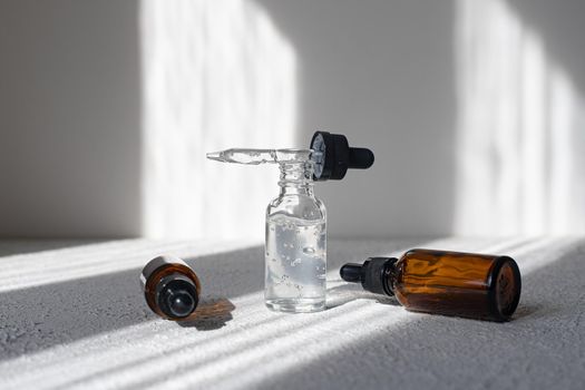 Glass bottle of mineral beauty oil with dropper for skin, hair. Product packaging serum on a white background. Women's cosmetics skin care cream with shadows. Copy space