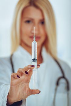 Close-up injections with a liquid, in the hands of a pretty blonde nurse with a face out of focus.