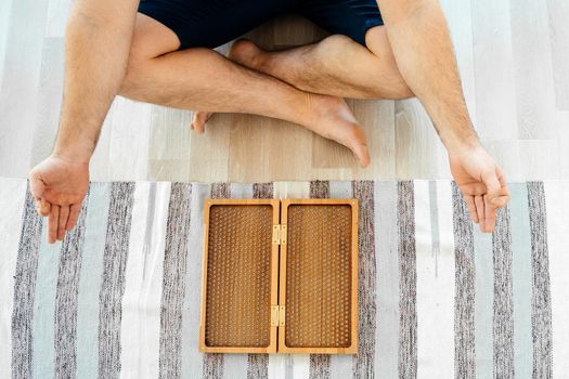Man exercising yoga meditating and sitting on the floor near sadhu board