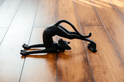 Ceramic black cat figurine bending doing yoga pose with copy space