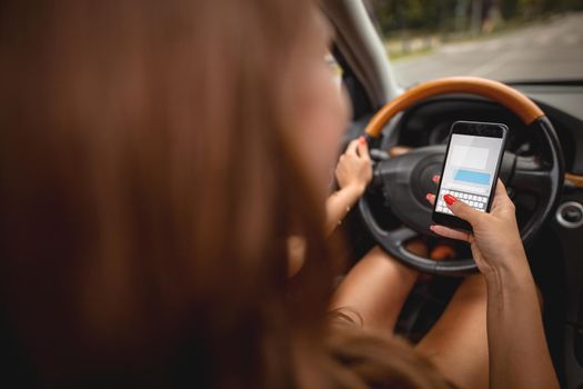 Woman texting on smartphone while driving a car.