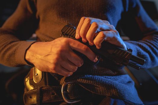 Close-up on a hands of a man carrying a gun with a bullet in the chamber, prepare to use to rob or kill someone.