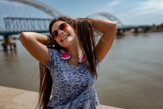 A beautiful cheerful gir having fun with your hair in the open and enjoying on the city rivershore on a beautiful summer day.