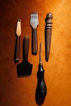 Production of handicrafts from genuine leather. Tools for making leather goods and pieces of brown leather. Production of leather products. View from above