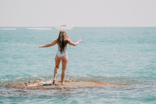 Woman sea yoga. Back view of free calm happy satisfied woman with long hair standing on top rock with yoga position against of sky by the sea. Healthy lifestyle outdoors in nature, fitness concept.