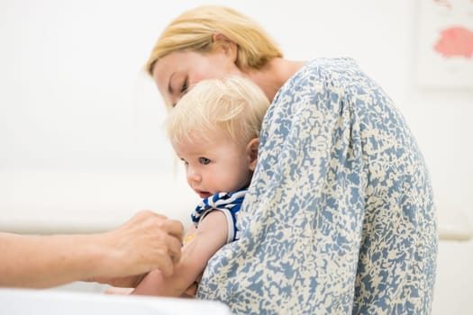 child beeing vaccinated by pediatrician in presence of his mother. Preventive vaccination against Diphtheria, whooping cough, tetanus, hepatitis, haemophilus influenzae, pneumococcus, poliomyelitis.