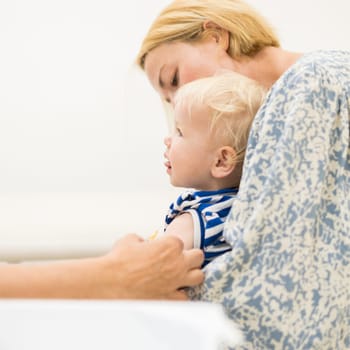 child beeing vaccinated by pediatrician in presence of his mother. Preventive vaccination against Diphtheria, whooping cough, tetanus, hepatitis, haemophilus influenzae, pneumococcus, poliomyelitis.