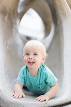 Child playing on outdoor playground. Toddler plays on school or kindergarten yard. Active kid on stone sculpured slide. Healthy summer activity for children. Little boy climbing outdoors