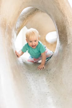 Child playing on outdoor playground. Toddler plays on school or kindergarten yard. Active kid on stone sculpured slide. Healthy summer activity for children. Little boy climbing outdoors