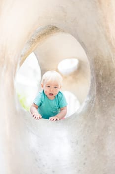 Child playing on outdoor playground. Toddler plays on school or kindergarten yard. Active kid on stone sculpured slide. Healthy summer activity for children. Little boy climbing outdoors