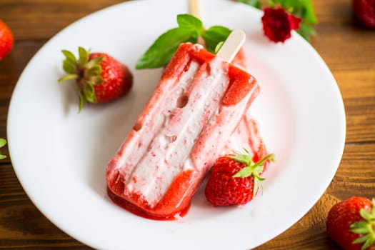 cooked homemade strawberry ice cream on a stick in a plate with strawberries