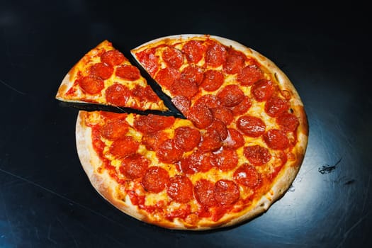 Sliced pizza with sausage, tomato sauce, mozzarella, onion and dough rim, topped with cream cheese on a black background