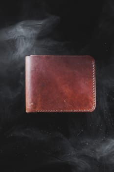 Stylish handmade brown leather wallet on a gray background. Product made of genuine leather.