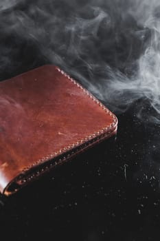 Stylish handmade brown leather wallet on a gray background. Product made of genuine leather.