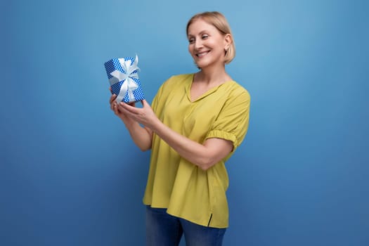 blond middle-aged woman holding a gift box in her hands for the holiday.