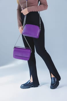 A purple leather bag in a girl's hand. Woman with luxury bag.