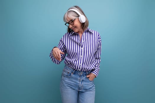 energetic retired woman with gray hair getting acquainted with gadgets for music on a bright studio background.