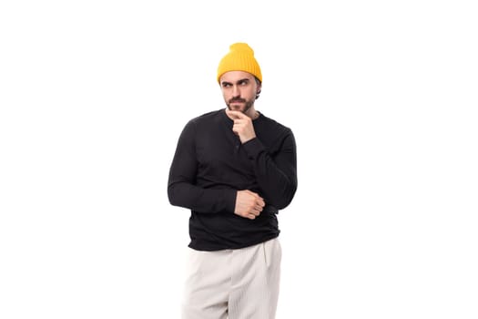 young brutal brunette european brutal man in a black sweatshirt on a white background with copy space.