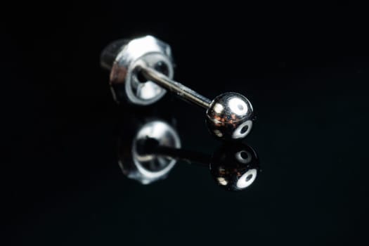 Silver earring macro photo with a precious stone on a black isolated background