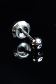 Silver earring macro photo with a precious stone on a black isolated background