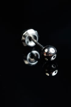 Silver earring macro photo with a precious stone on a black isolated background
