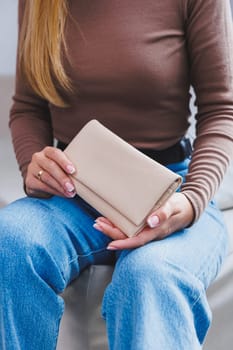 A beautiful woman holds a beige leather purse in her hands. Small women's handbag