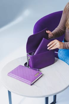 A purple leather bag in a girl's hand. Woman with luxury bag.