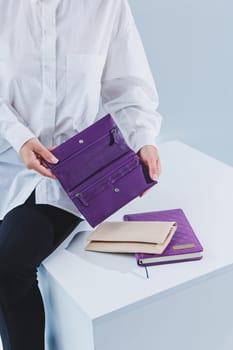 A stylish woman holds a purple leather purse in her hands. Small women's handbag