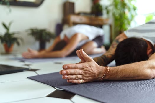 Home is where your yoga mat is. two men going through a yoga routine at home
