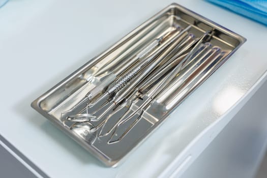 Tray with metal dental tools. Tools of the dentist. Interior of a patient reception room with dental equipment in a dental clinic.