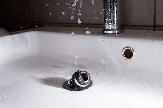Broken tap in the bathroom sink. Splashing water from a silver faucet. Selective focus