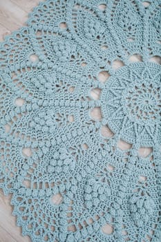 In a bright room on the floor there is a round blue handmade carpet. flooring, natural cotton. Blue knitted handmade carpet on the floor