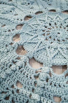 In a bright room on the floor there is a round blue handmade carpet. flooring, natural cotton. Blue knitted handmade carpet on the floor