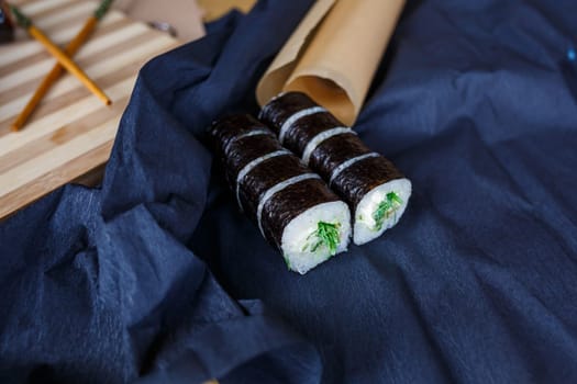 Set of traditional japanese food on a dark background. Sushi rolls, nigiri, raw salmon steak, rice, cream cheese, avocado, lime, pickled ginger. Asian food frame.