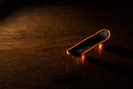 A finger skateboard stands on a wooden background. Toys for the development of fine motor skills of fingers