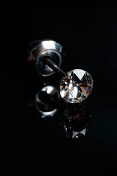 Silver earring macro photo with a precious stone on a black isolated background. Selective focus.