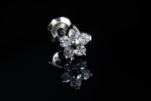 Jewelry with stone earrings, luxury silver earrings with diamonds, sapphires on a black background. Selective focus.