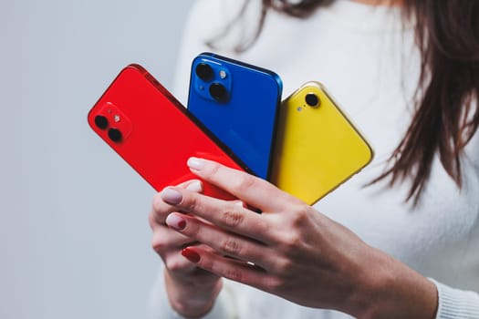 New bright phones in the hands of a woman. Hands of a woman holding several smartphones.