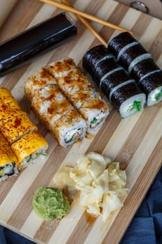 Sushi set with different types of rolls and sashimi made from eel, salmon, tuna, shrimp, red caviar and tobiko flying fish roe. Pan-Asian and Asian food and dishes on a black concrete kitchen table.