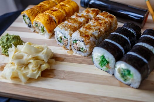 Set of traditional Japanese dishes. Sushi rolls, nigiri, raw salmon, rice, cream cheese, avocado, pickled ginger.